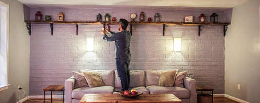 Person installing shelves on a wall in a living room.